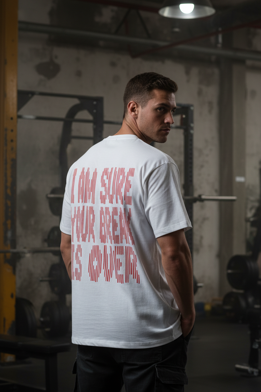 A man at the gym wears the Oversize Shirt BreakOver, featuring bold red text on the back that says, "I am sure your break is over," with gym equipment and weights in the background.